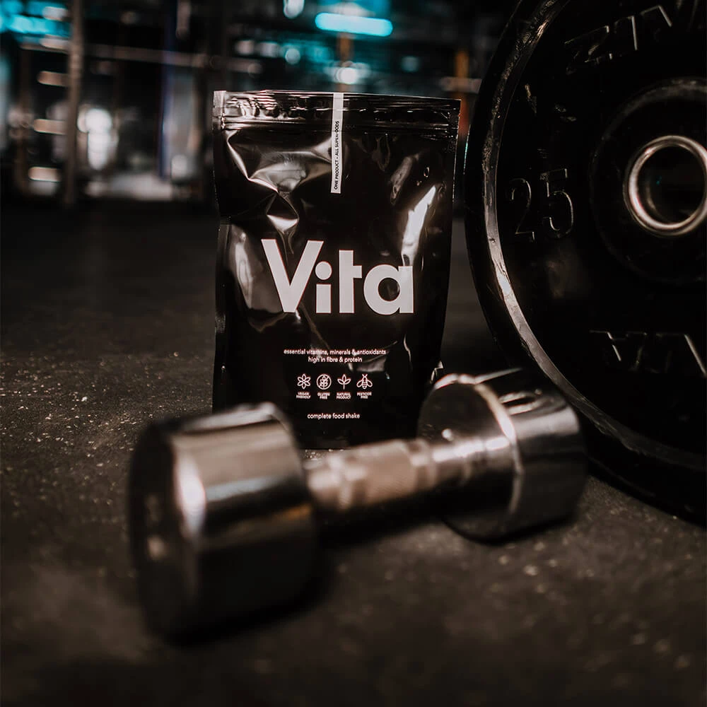 Vita Shake od Raypath obok hantli – pożywny shake dietetyczny dający uczucie sytości po treningu.